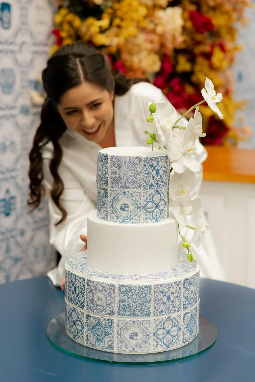 Bolo de casamento com azulejos portugueses e orquídeas brancas em momento de celebração da noiva, criação da Alegra Cakes em Florianópolis